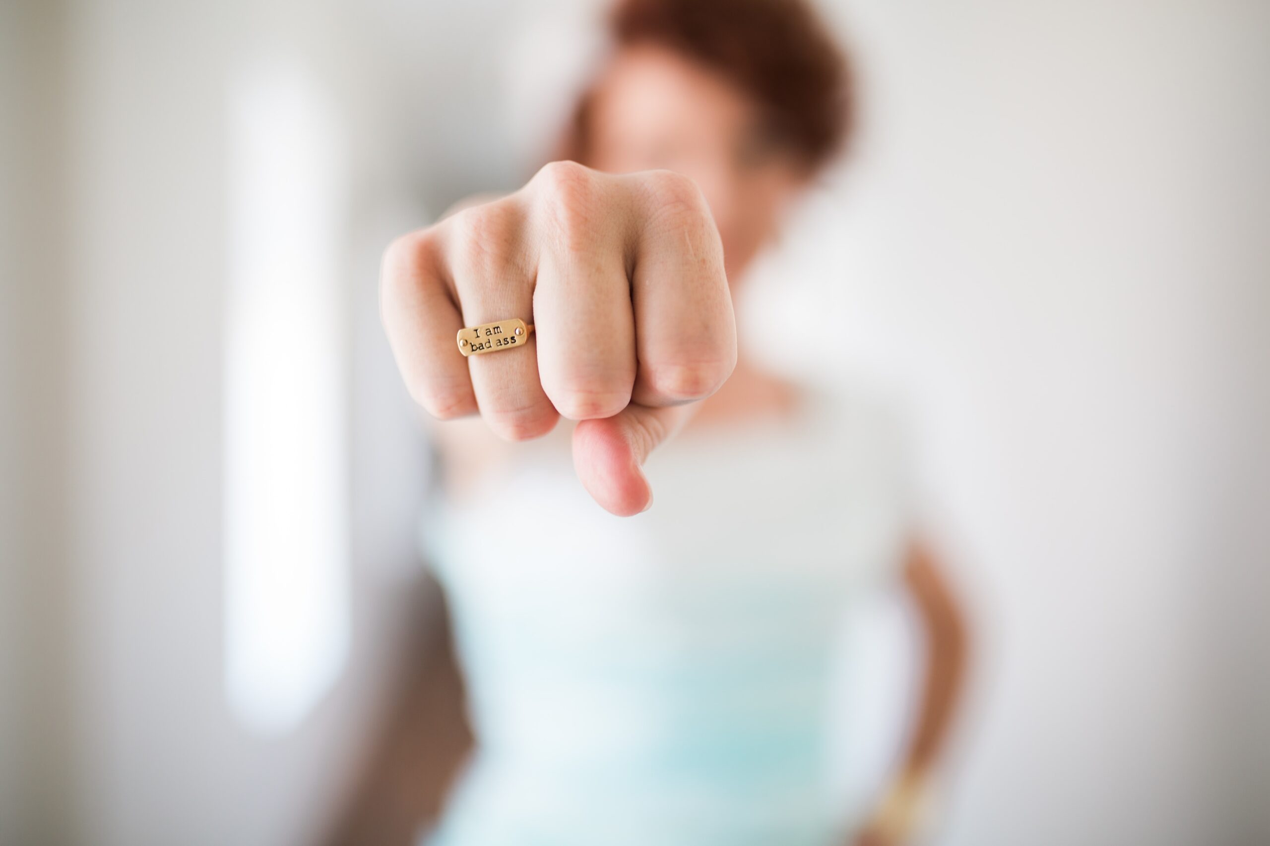 woman's fist wearing gold ring with words I am bad ass
