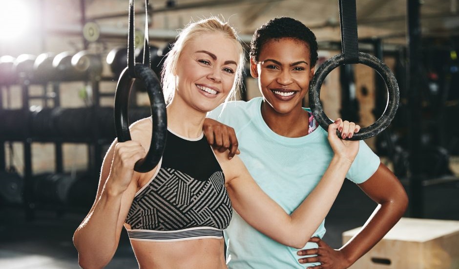 Two smiling female gym owners wearing workout clothes