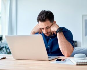 confused business owner staring at balance sheet on laptop